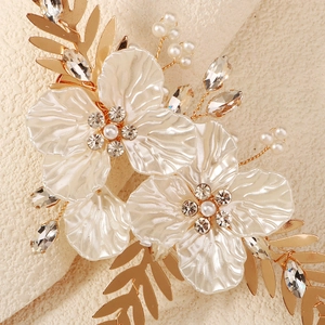 Détail de pétales blanc nacré avec accents de feuilles dorées et centre en cristal