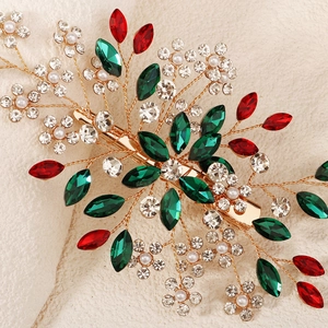 Detailed close-up of handmade bridal clip with red and green gems and white pearls