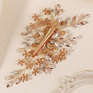 Close-up of handmade golden bridal hair clip with crystal leaves and floral details