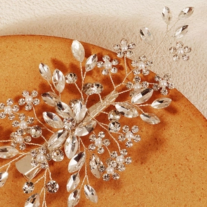 Macro detail of bridal hair clip showing silver wire floral design with crystals and pearls