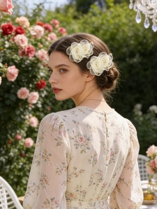 Dettaglio di due fermagli per capelli con fiori di tulle color crema su uno chignon