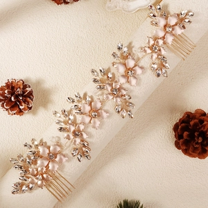 Detail von rosa Emaille-Blumen und Kristallblatt-Rebe auf goldenem Brauthaarkamm