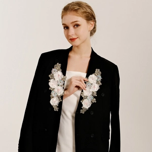 Detailed close-up of 3D floral fabric patches with rhinestones on a white bridal gown