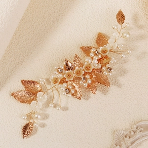 Détail de la pince à cheveux de mariée avec feuilles dorées, fleurs et perles