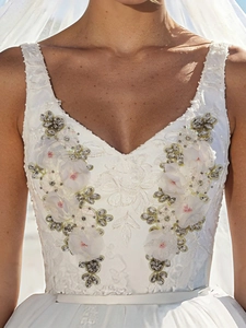 Close-up of 3D fabric flower appliques with rhinestones on a white bridal gown