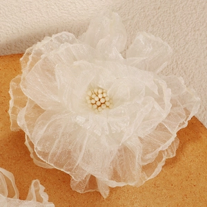 Dettaglio macro del fermaglio per capelli a fiore in rete crema con perla centrale