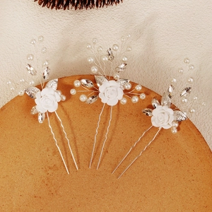 Détail de trois épingles à cheveux faites main avec roses blanches, perles et cristaux