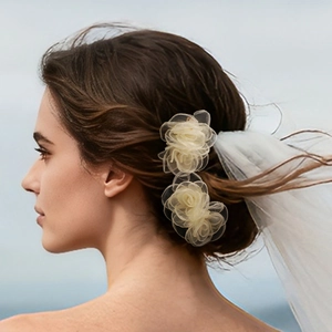 Dettaglio di fermagli per capelli a rosa in organza crema per un look da sposa romantico