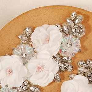 Detailed macro view of handcrafted white fabric flower patch with sparkling rhinestones