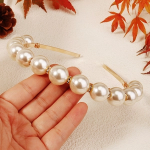 Close-up of luxury white oversized pearls and rhinestone spacers on a gold headband