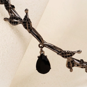 Detail of gothic black leaf crown featuring a teardrop crystal and intricate metalwork
