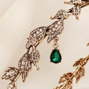 Detailed macro view of vintage gold bridal crown with emerald teardrop pendant and crystals