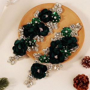 Macro detail of dark green fabric flower patches with emerald rhinestones and embroidery
