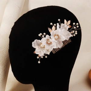 Detail showing white tulle flowers and pearl beads on a bridal hair comb accessory