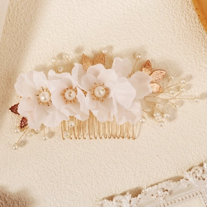 Vintage floral bridal hair comb with pearls and gold leaves on a textured background