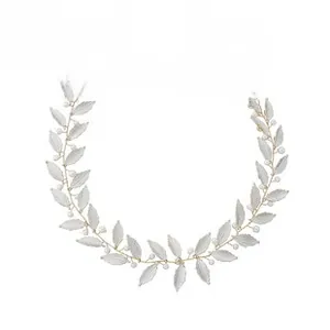 Detailed shot of handmade bridal headband with gold leaves, white pearls and satin ribbons