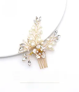 Détail du peigne de mariée avec perles en fil d'or et cristaux sur une plaque blanche
