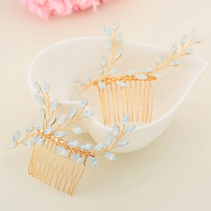 Detail of handmade gold hair combs with blue crystal leaves in a heart-shaped ceramic dish