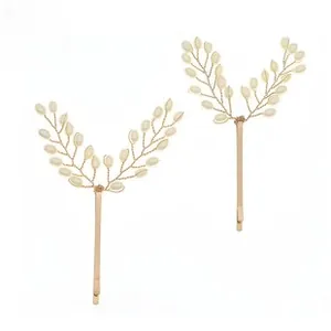 Detail of handmade golden bridal leaf hair clips with white pearls in a delicate wire design
