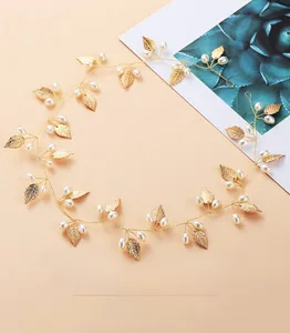 Détail d'un bandeau de mariée avec feuilles dorées et perles blanches sur fil