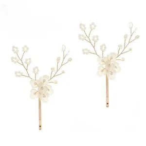 Close-up of handmade gold bridal hair clips with white 3D flowers and pearls details