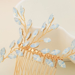 Detail of handmade gold hair comb with light blue leaf-shaped stones and branch wire design