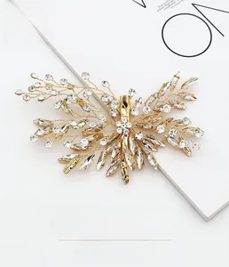 Macro detail of golden bridal hair clip with intricate rhinestone flower and leaf design