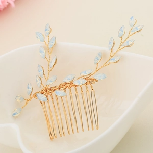 Handmade gold hair comb with blue opal rhinestones in a branch design on ceramic plate