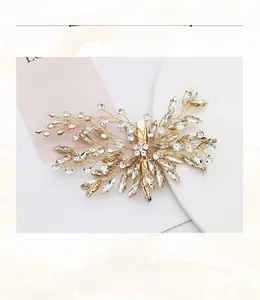 Close-up of handmade bridal leaf hair clip with rhinestones and gold alloy wire details
