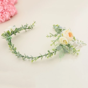 Détail d'un bandeau de mariée fait main avec feuilles vertes et roses en soie crème