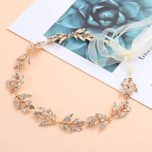 Detail of golden bridal leaf headband with sparkling rhinestones and white ribbon ties