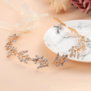Close-up of golden leaf bridal headband with crystals and white ribbon ties