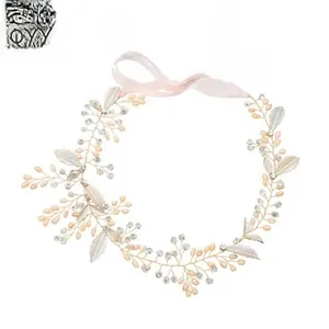 Detail of handcrafted bridal headband with gold wires, white leaves, pearls and rhinestones