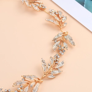 Close-up of golden bridal hair vine featuring intricate alloy leaves with crystals