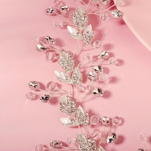 Détail macro de vigne à cheveux argentée pour mariée avec feuilles en cristal et strass