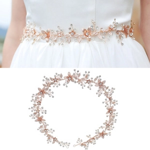 Dettaglio della cintura da sposa in oro rosa con strass scintillanti e perle bianche