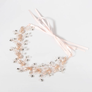 Détail d'un bandeau de mariée fait main avec feuilles en or rose, cristaux et rubans