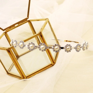 Close-up of floral pearl headband with rhinestone embellishments on silver metal base