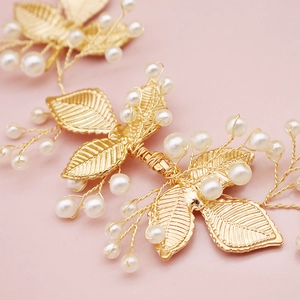 Détail de peigne à cheveux de mariée avec feuilles dorées et perles blanches élégantes