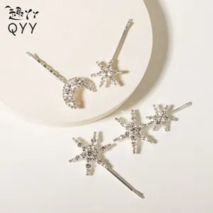Détail de barrettes à cheveux argentées avec strass en forme de lune et d'étoiles