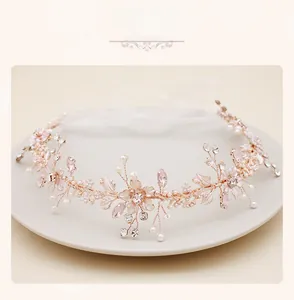 Détail d'un bandeau de mariée en or rose avec pétales roses, perles et cristaux sur plateau