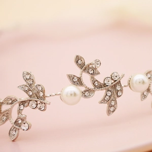 Cerchietto da sposa in argento con strass lucidi, foglie e perle bianche su sfondo rosa
