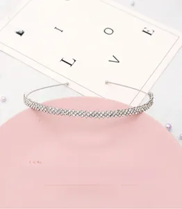 Close-up of minimalist bridal headband with rows of shimmering rhinestones on silver base