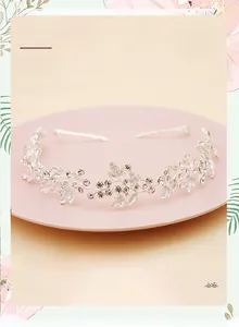 Macro detail of bridal silver hair band with intricate leaf patterns and sparkly rhinestones