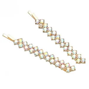 Détail de deux barrettes en métal doré avec des strass irisés dans un design en dégradé