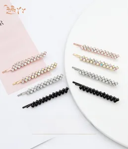 Macro shot of sparkling rhinestone bobby pins in four colors on a white tray