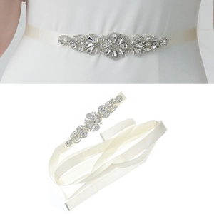 Close-up of bridal belt with luxury rhinestone flower pattern on white satin ribbon