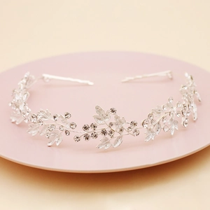 Silver bridal headband featuring leaf designs and rhinestones on a pink plate