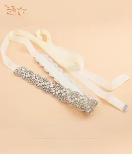 Macro shot of ivory satin wedding belt with sparkling crystal rhinestones and wave patterns