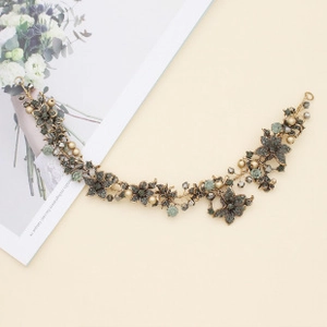 Close-up of vintage bridal hair band with crystals, pearls and green floral details